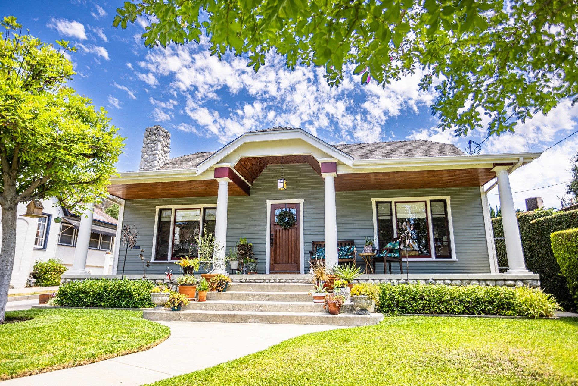 Charming blue house with columns, front yard garden, and clear skies.