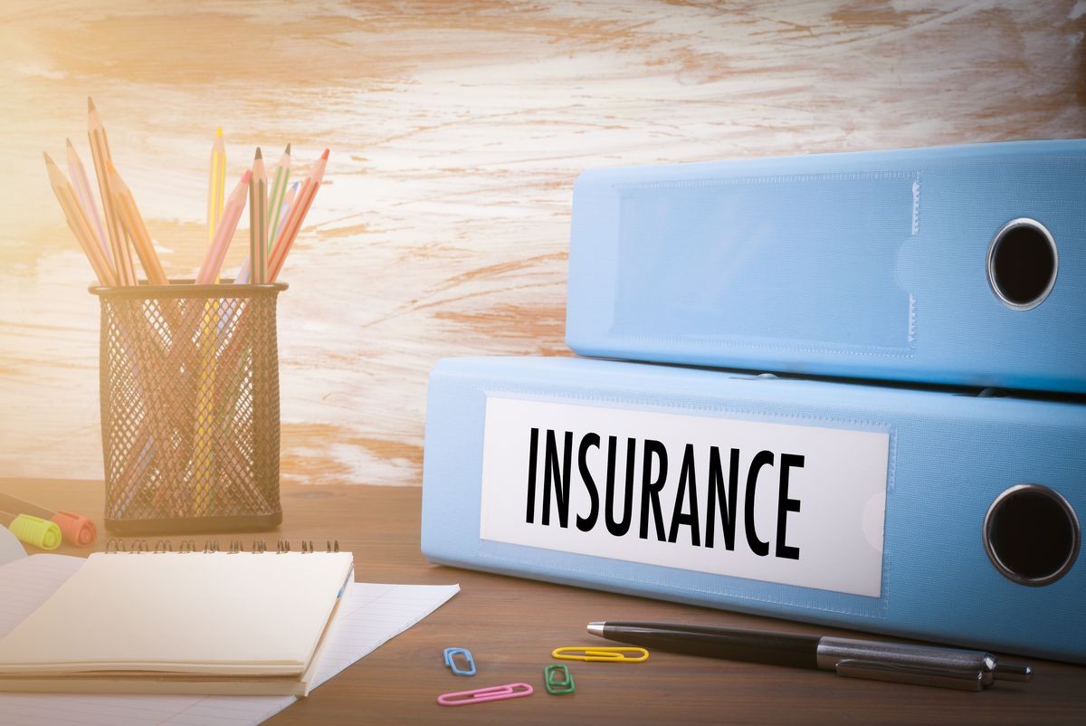 insurance, Office Binder on Wooden Desk. On the table colored pencils, pen, notebook paper