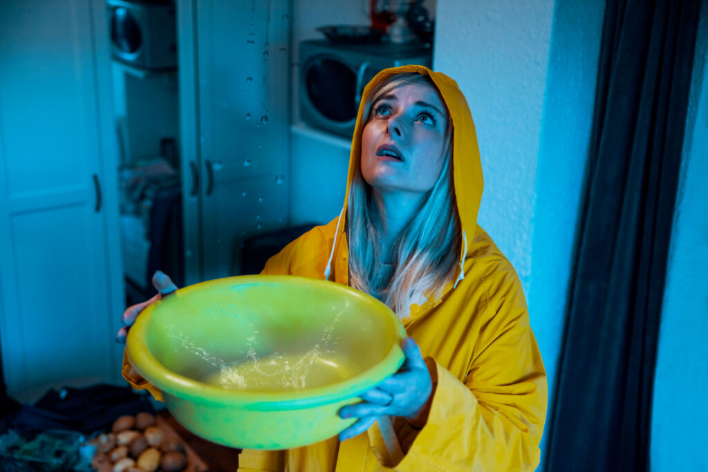 Homeowner collecting water from a storm-related ceiling leak